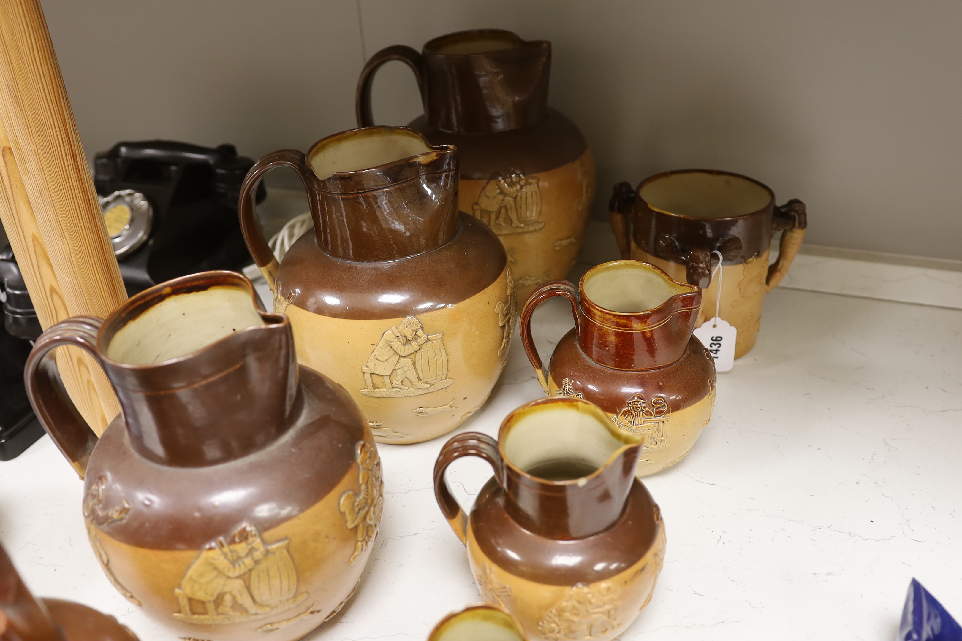 Eight Doulton stoneware jugs and a tyg, largest 27cm high